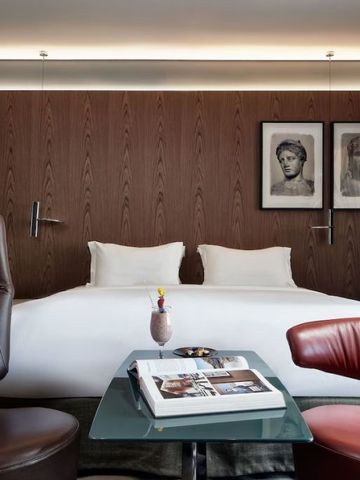 Modernes Doppelzimmer mit zwei Sesseln und Kunstwerken an der Wand.