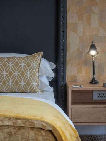 Modernes Schlafzimmer mit gelbem Akzentkissen und Stehlampe