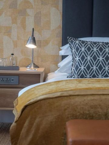 Detail eines Bettes mit eleganter Bettwäsche und Leselampe