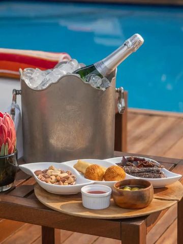 Holztisch mit Champagnerflasche und Snacks am Pool