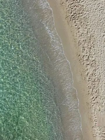 Luftaufnahme eines sandigen Strandes mit kristallklarem Wasser