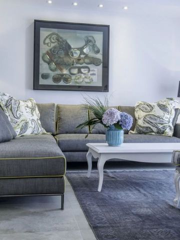 Heller Wohnbereich mit grauen Sofas, Kunstgemälde an der Wand und eleganter Dekoration