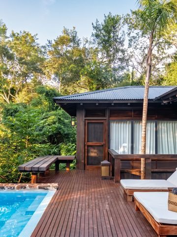 Privater Pool auf Holzdiele mit Liegen umgeben von dichtem Grün