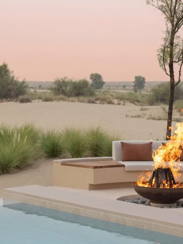 Außenbereich mit Feuerstelle, Pool und Wüstenlandschaft im Hintergrund im Hotel Bab Al Shams