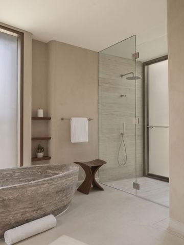 Modernes Badezimmer mit großer Steinbadewanne und Glasdusche