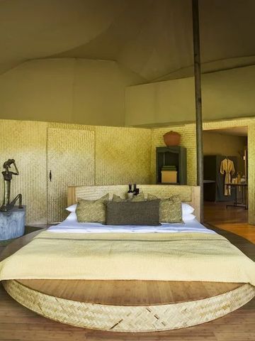 Großes Doppelbett in stilvollem Zimmer der Banjaar Tola Safari Lodge