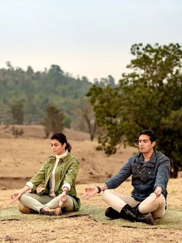 Personen beim Meditieren auf einer Wiese im Kanha-Nationalpark