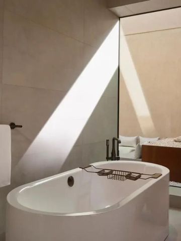 Freistehende Badewanne mit natürlichem Licht und Blick auf eine Pflanze