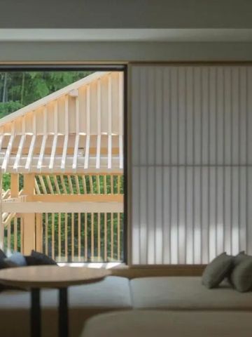 Modernes Hotelzimmer mit Blick auf traditionelle Holzarchitektur und Grünfläche