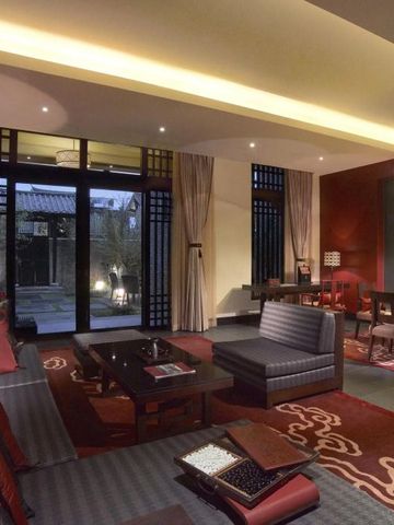 Luxuriös eingerichtetes Wohnzimmer in einer Suite des Banyan Tree Lijiang mit stilvollen roten Akzenten
