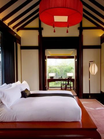 Großer Schlafbereich mit Himmelbett im Banyan Tree Lijiang mit Blick ins Grüne