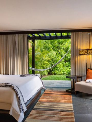 Luxuriöse Suite mit großen Fenstern, Blick auf tropischen Garten und Hängematte