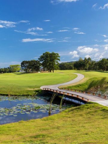 Golfplatz mit Brücke und Teich unter blauem Himmel