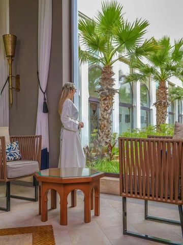 Frau steht in Lounge mit Blick auf einen grünen Garten durch große Fenster