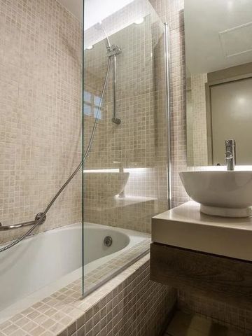 Gefliestes Badezimmer mit Badewanne und elegantem Waschbecken.