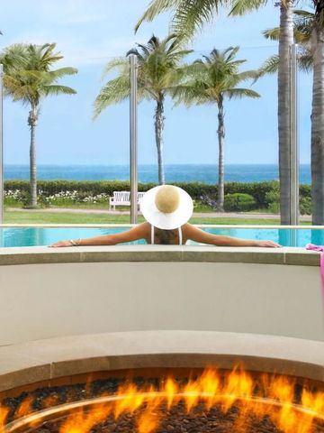 Frau im Pool mit Blick auf das Meer und Palmen im Hintergrund
