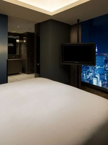 Luxuriöses Zimmer mit großem Bett und atemberaubendem Blick auf die Stadt bei Nacht