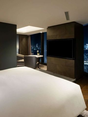 Helles Zimmer mit großem Bett und Panoramafenster mit Stadtblick bei Nacht