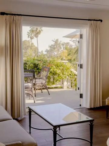 Helle Suite mit Balkonblick auf Garten und Palmen.