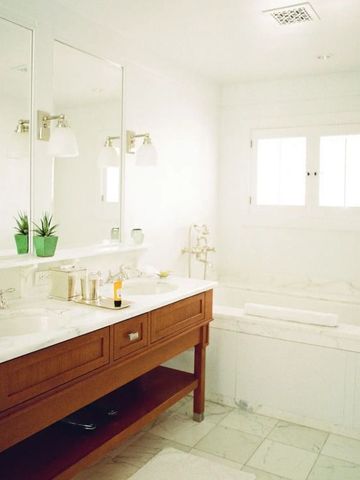 Helles Badezimmer mit Marmorarbeitsplatte und Badewanne.