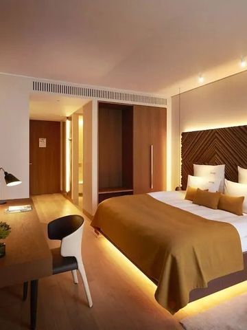 Modernes Hotelzimmer mit beleuchtetem Kopfteil und Schreibtisch
