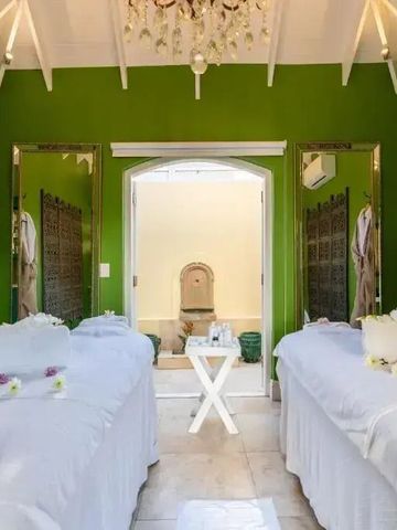 Wellnessbereich mit grünen Wänden und zwei Massageliegen.