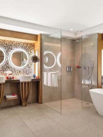 Luxuriöses Badezimmer mit freistehender Badewanne und Doppelwaschbecken mit beleuchteten Spiegeln