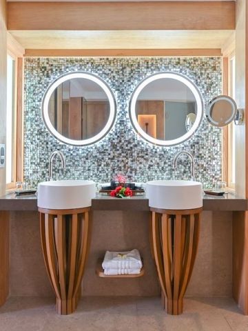 Stylische Doppelwaschbecken mit runden, beleuchteten Spiegeln und Mosaikfliesen