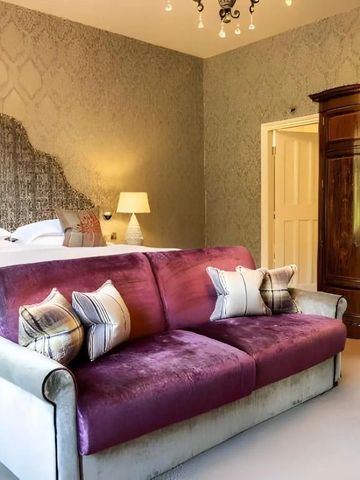 Gemütliches Schlafzimmer mit lila Sofa und klassischem Kleiderschrank