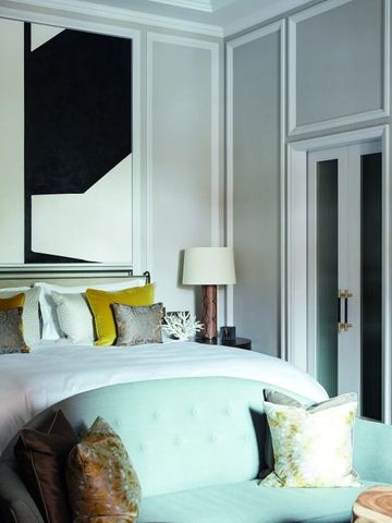 Luxuriöses Hotelzimmer mit großem Bett, Dekokissen und moderner Kunst an der Wand