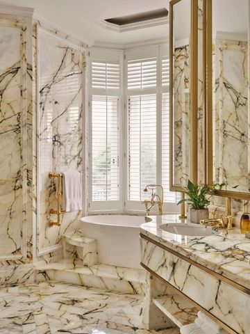 Luxuriöses Badezimmer mit Marmorwänden und freistehender Badewanne
