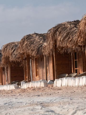 Reihe von Strandbungalows mit Strohdächern am Sandstrand