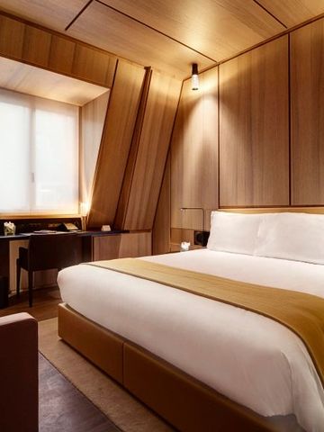 Helles, modernes Hotelzimmer mit luxuriösem Bett und Holzdetails