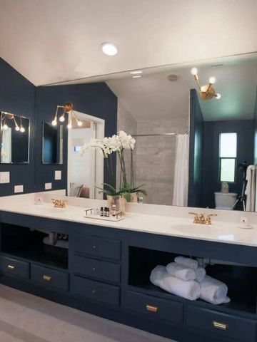 Elegantes Badezimmer mit dunklem Schminktisch und großer Spiegelwand