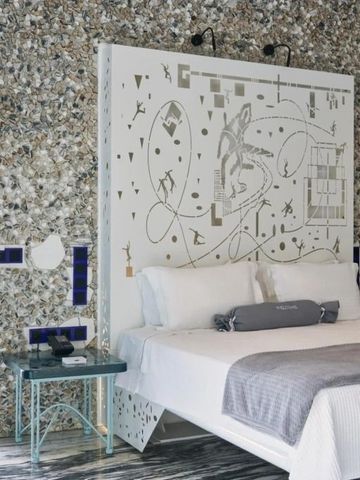Hotelzimmer mit kunstvoll gestaltetem Kopfteil und Mosaiksteinwänden