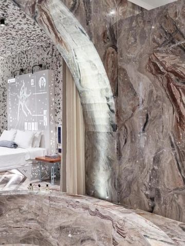 Luxuriöses Hotelzimmer mit kunstvoll gemusterten Wänden und modernem Bett.