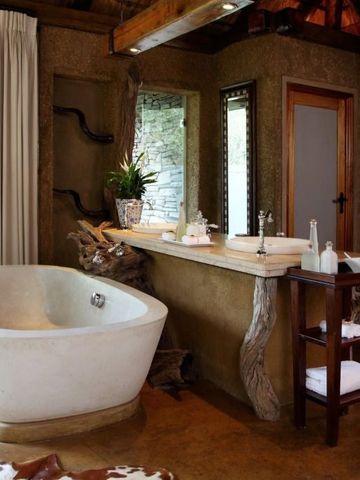 Luxuriöses Badezimmer mit freistehender Badewanne und Natursteinwänden