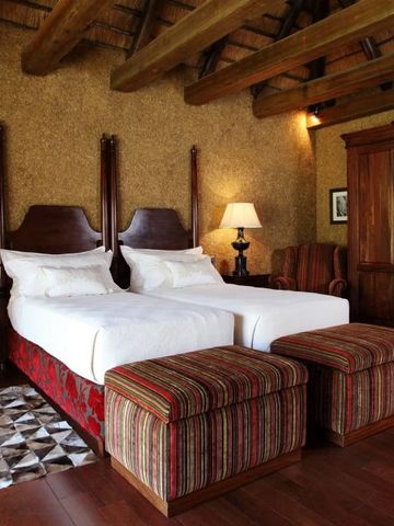 Luxuriöses Gästezimmer mit zwei Einzelbetten und Holzbalkendecke im Safari-Stil