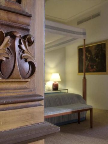 Detailaufnahme eines kunstvoll gestalteten Holzdetails neben einem luxuriösen Bett.