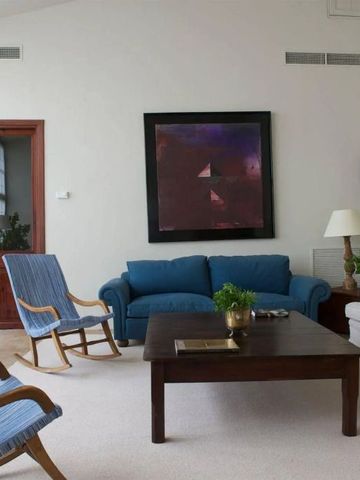 Helles Wohnzimmer mit blauen Sesseln und modernem Kunstwerk an der Wand
