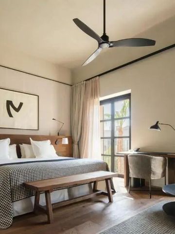 Elegantes Hotelzimmer mit großem Bett, modernem Ventilator und stilvollem Schreibtisch.