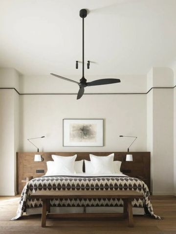Minimalistisch eingerichtetes Hotelzimmer mit Doppelbett und Deckenventilator.