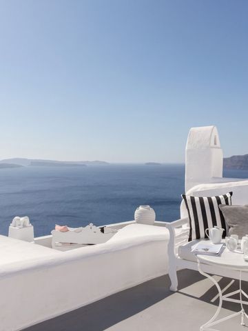 Sonnenterrasse mit Liegen und Blick auf die Ägäis. Elegant eingerichtet mit Kissen und Tisch.