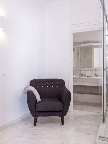 Helles Zimmer mit komfortablem Sessel und Dusche. Stilvolle weiße Einrichtung.