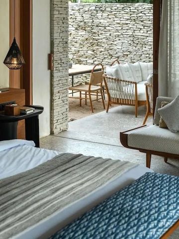 Offener Bereich mit Sofa und Essbereich im Freien mit Steinwand