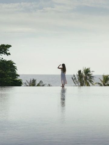 Infinity-Pool mit Blick aufs Meer und Palmen im Hintergrund