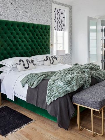 Luxuriöses Schlafzimmer mit grünem Samtkopfteil, eleganter Dekoration und Tageslicht.