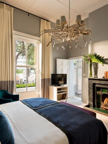 Elegantes Zimmer mit Kamin, großen Fenstern, blau-weißer Dekoration und Kronleuchter.
