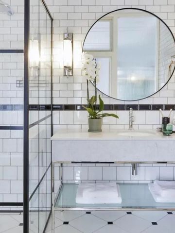 Elegantes Badezimmer mit Mosaikfliesen und rundem Spiegel.