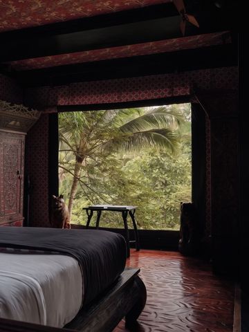 Elegantes Schlafzimmer mit großen Fenstern und üppigem Waldblick